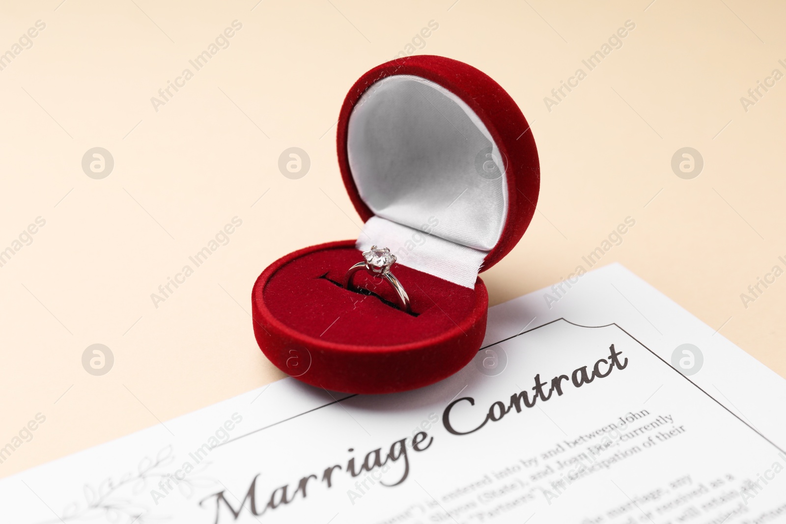 Photo of Marriage contract and ring on beige table, closeup