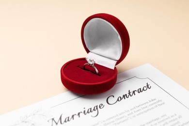 Photo of Marriage contract and ring on beige table, closeup