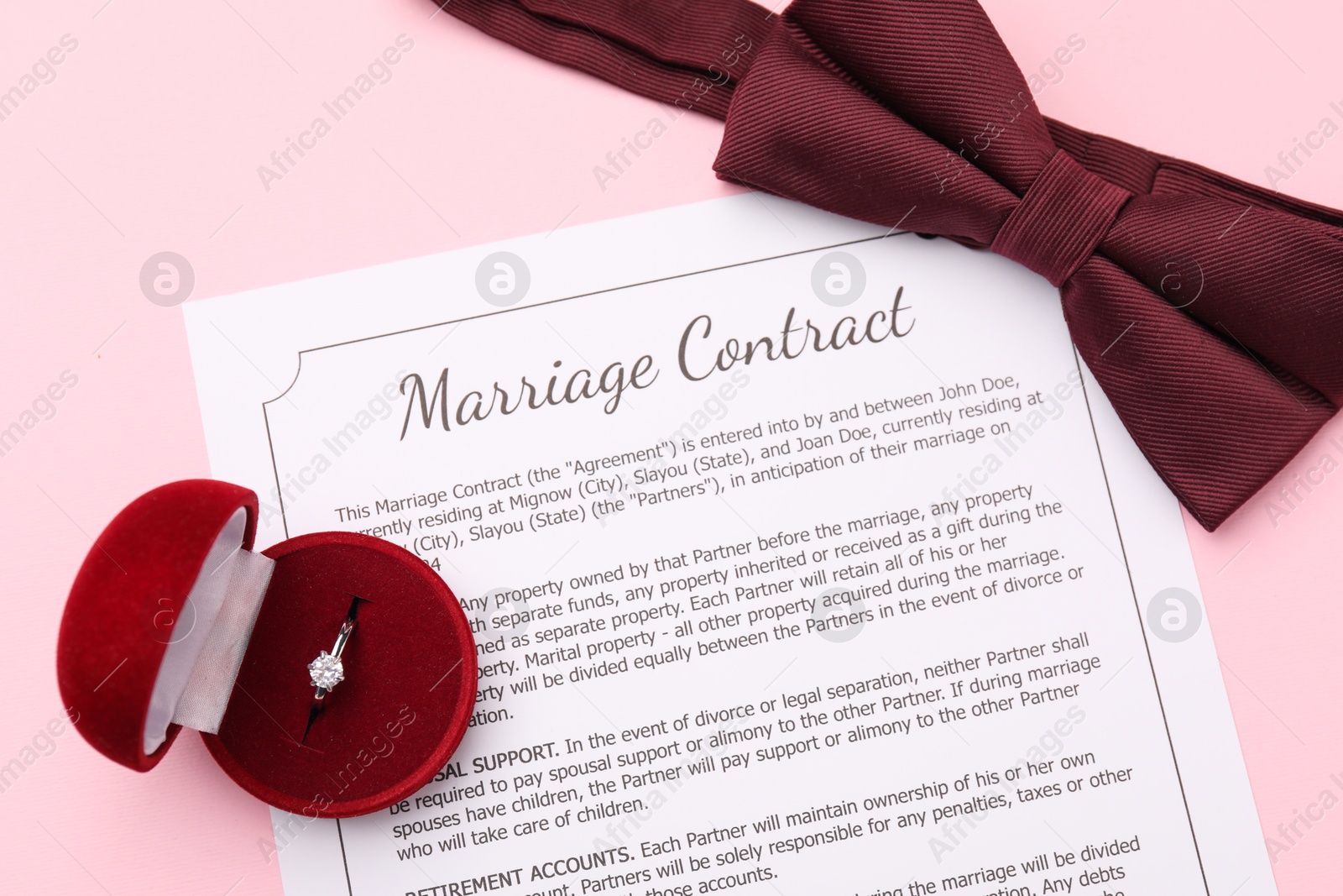 Photo of Marriage contract, bowtie and ring on pink background, top view