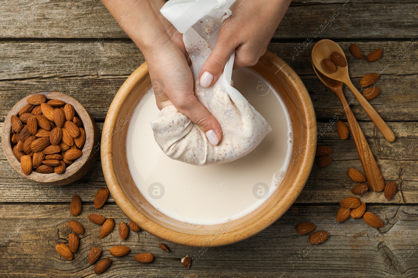 Photo of Woman making almond milk at wooden table, top view