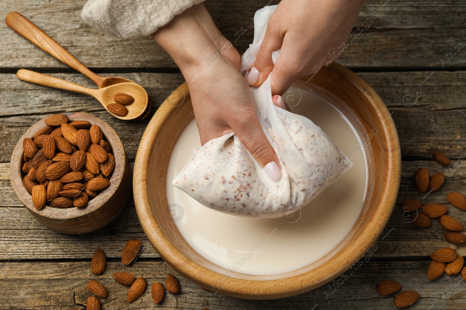 Photo of Woman making almond milk at wooden table, top view