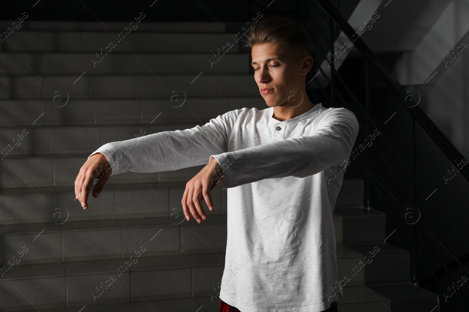 Photo of Young man suffering from sleepwalking on stairs indoors