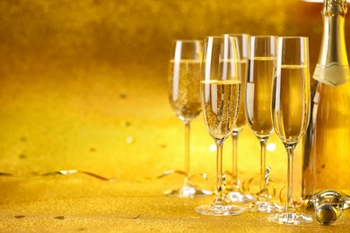 Photo of Champagne, bottle and streamers on golden background. Space for text