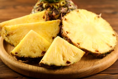 Photo of Cut fresh ripe pineapple on wooden table, closeup