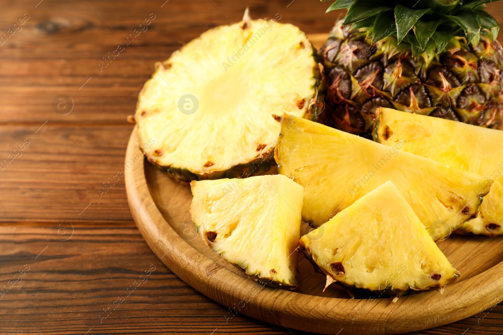 Photo of Cut fresh ripe pineapple on wooden table, closeup