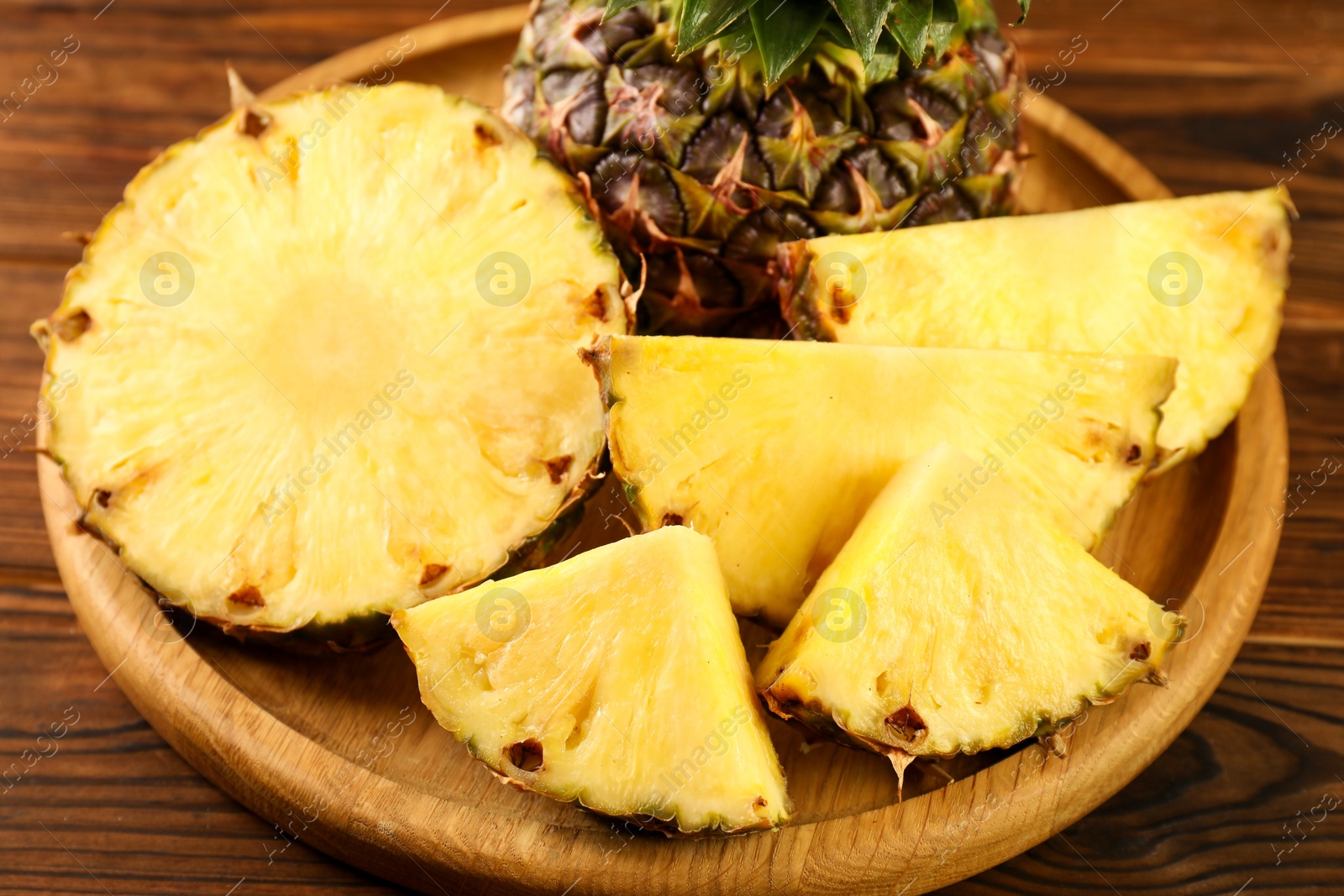 Photo of Cut fresh ripe pineapple on wooden table, closeup