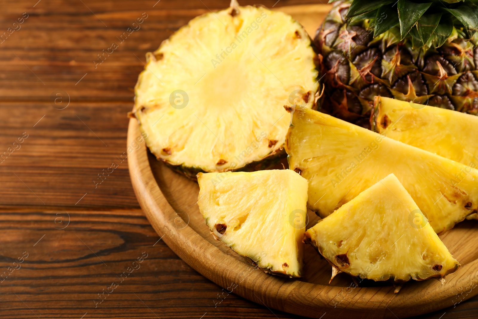 Photo of Cut fresh ripe pineapple on wooden table, closeup