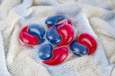 Photo of Laundry detergent capsules on color fabric, closeup