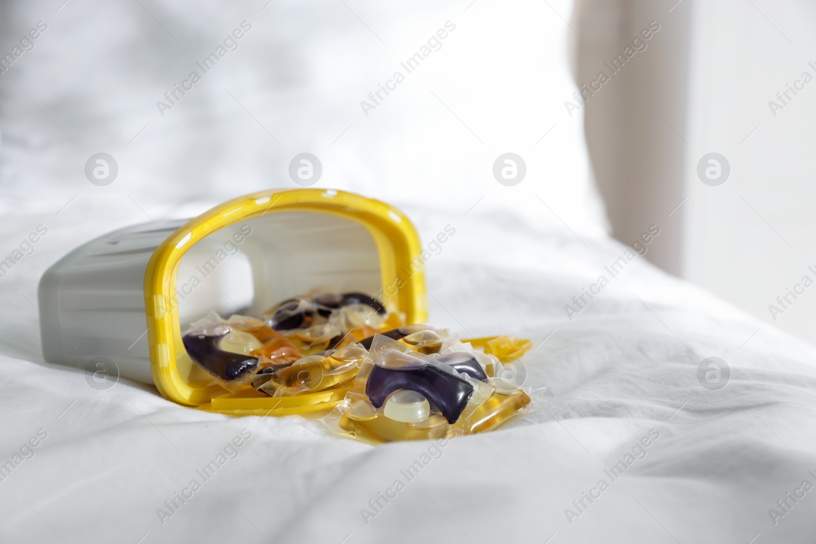 Photo of Laundry detergent capsules in container on white fabric, closeup. Space for text