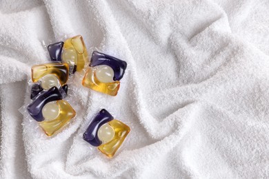 Photo of Laundry detergent capsules on white towel, closeup. Space for text