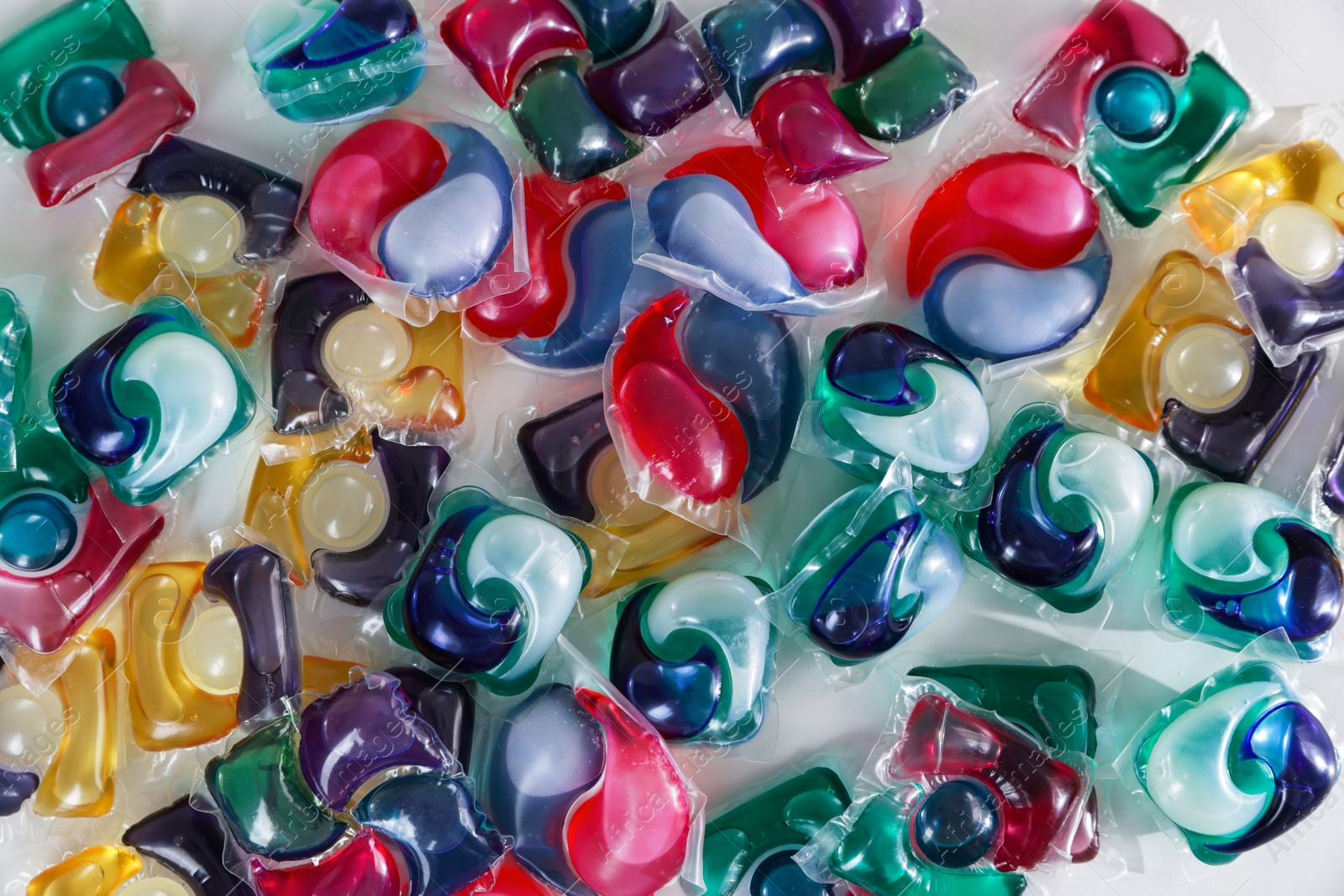 Photo of Different laundry detergent capsules on white background, top view