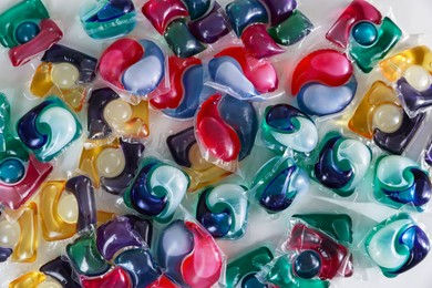 Photo of Different laundry detergent capsules on white background, top view