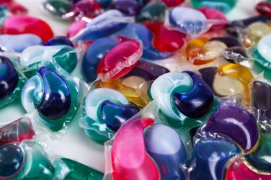 Photo of Different laundry detergent capsules on white background, closeup