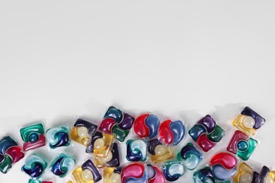 Photo of Different laundry detergent capsules on white background, top view. Space for text