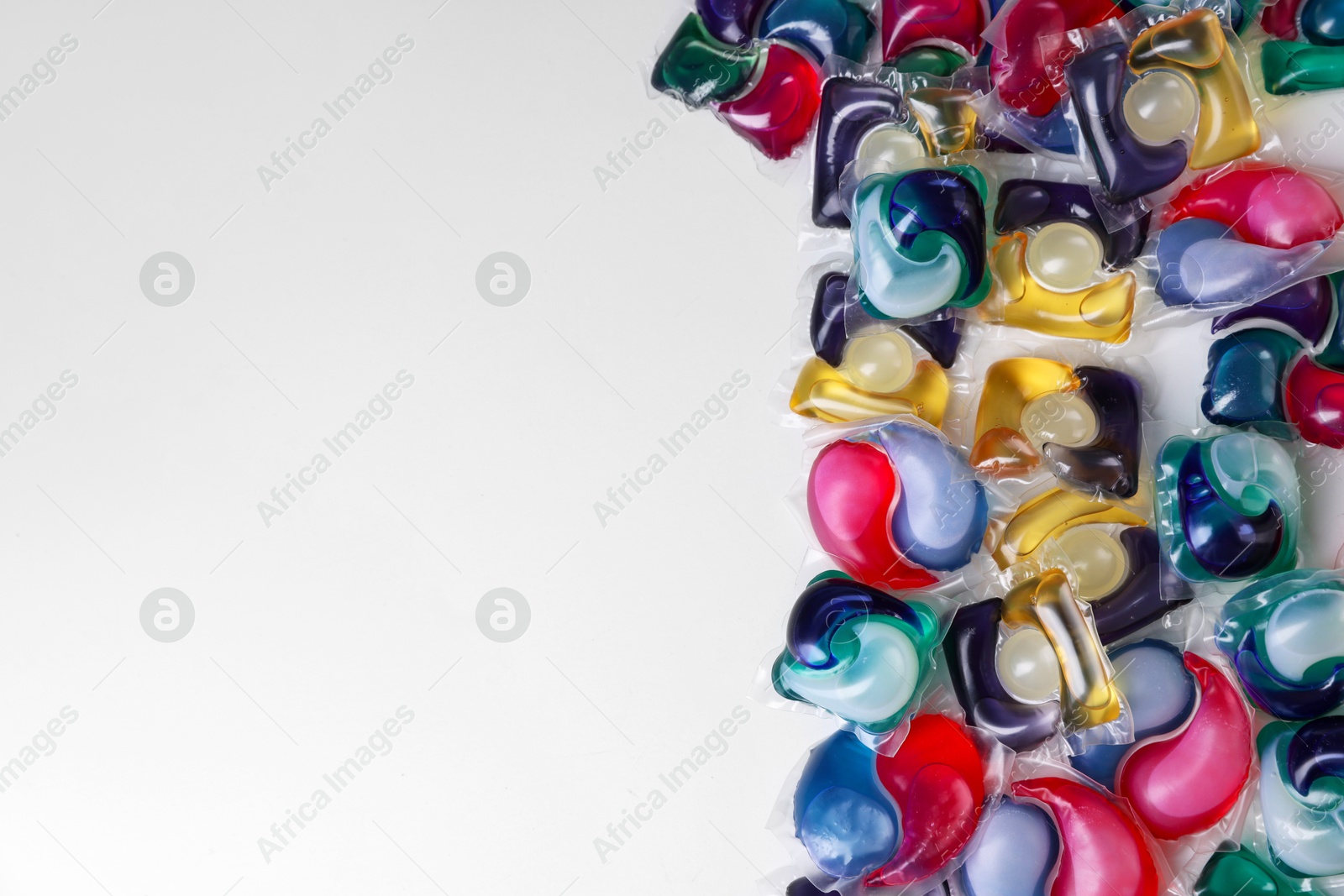 Photo of Different laundry detergent capsules on white background, top view. Space for text