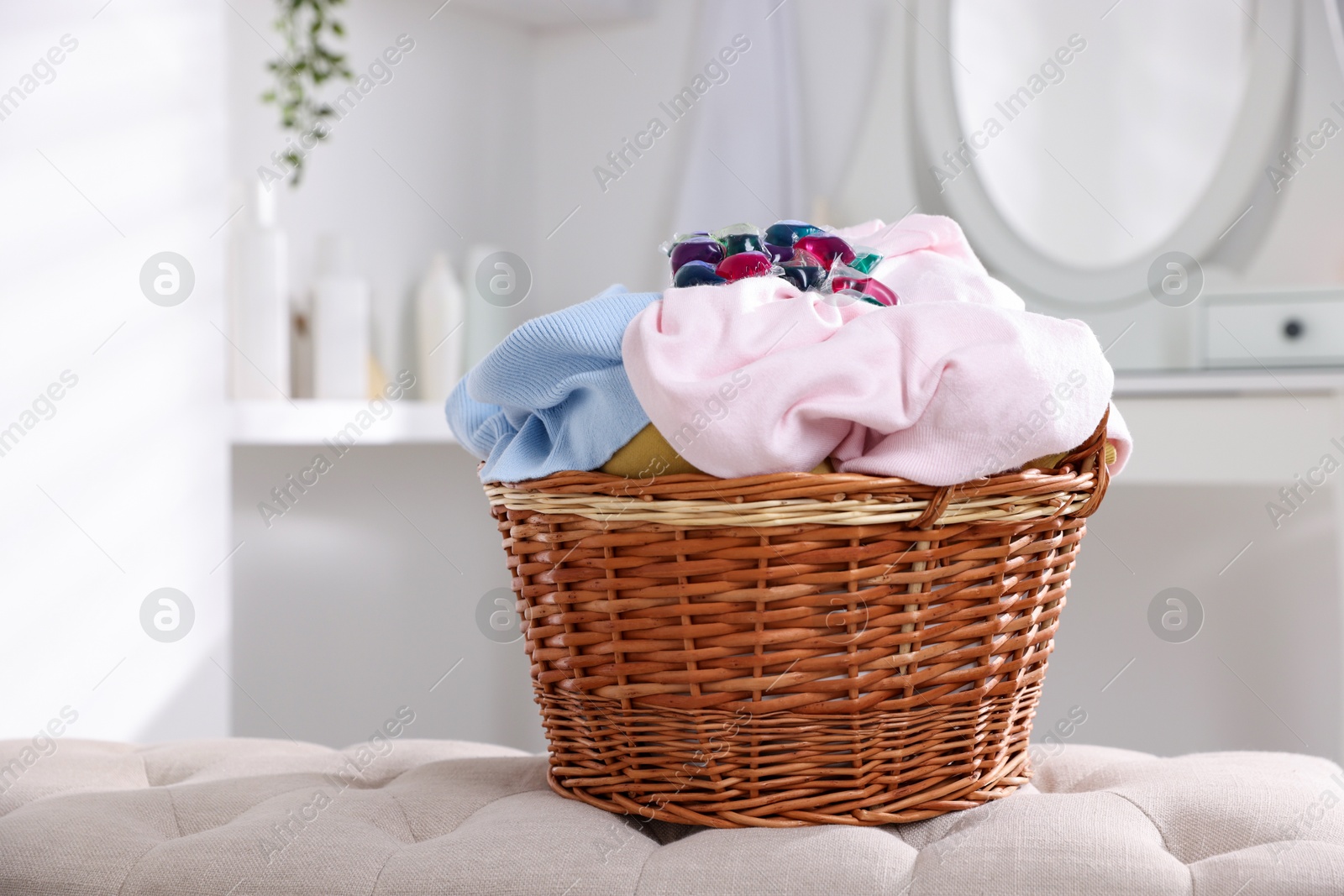 Photo of Laundry detergent and clothes in basket indoors