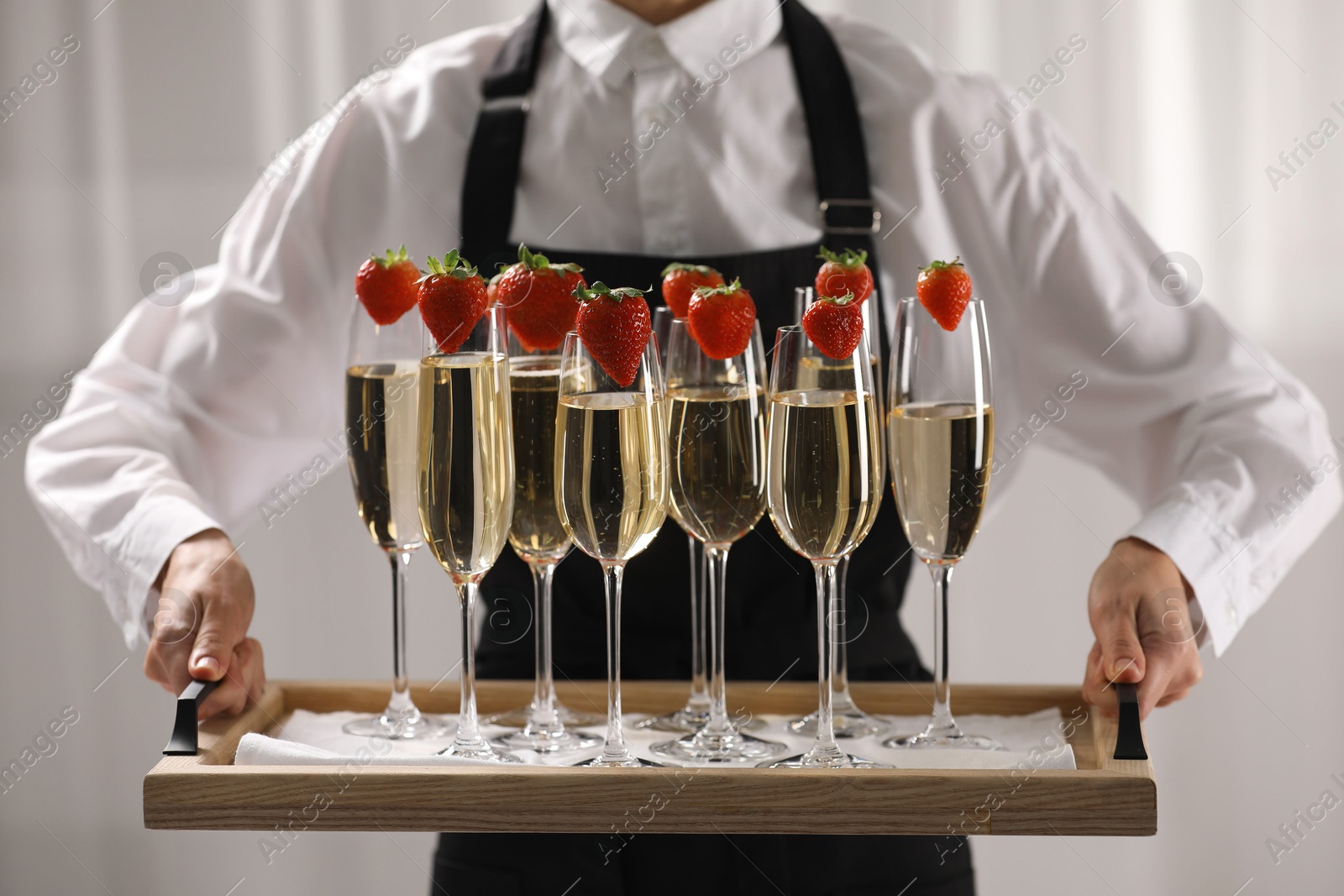 Photo of Waiter holding tray with glasses of champagne indoors, closeup