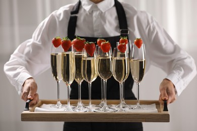 Photo of Waiter holding tray with glasses of champagne indoors, closeup