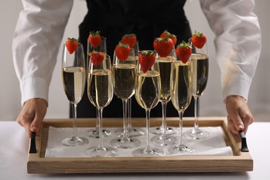 Photo of Waiter holding tray with glasses of champagne indoors, closeup