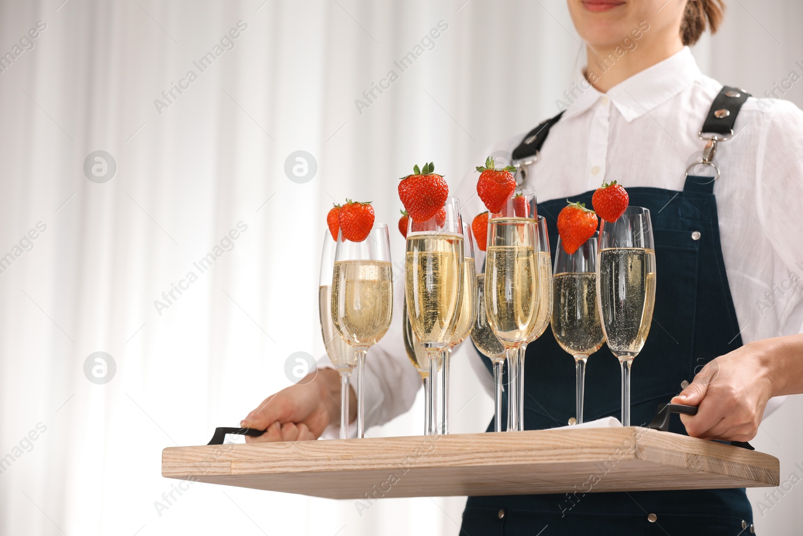 Photo of Waiter holding tray with glasses of champagne indoors, closeup. Space for text