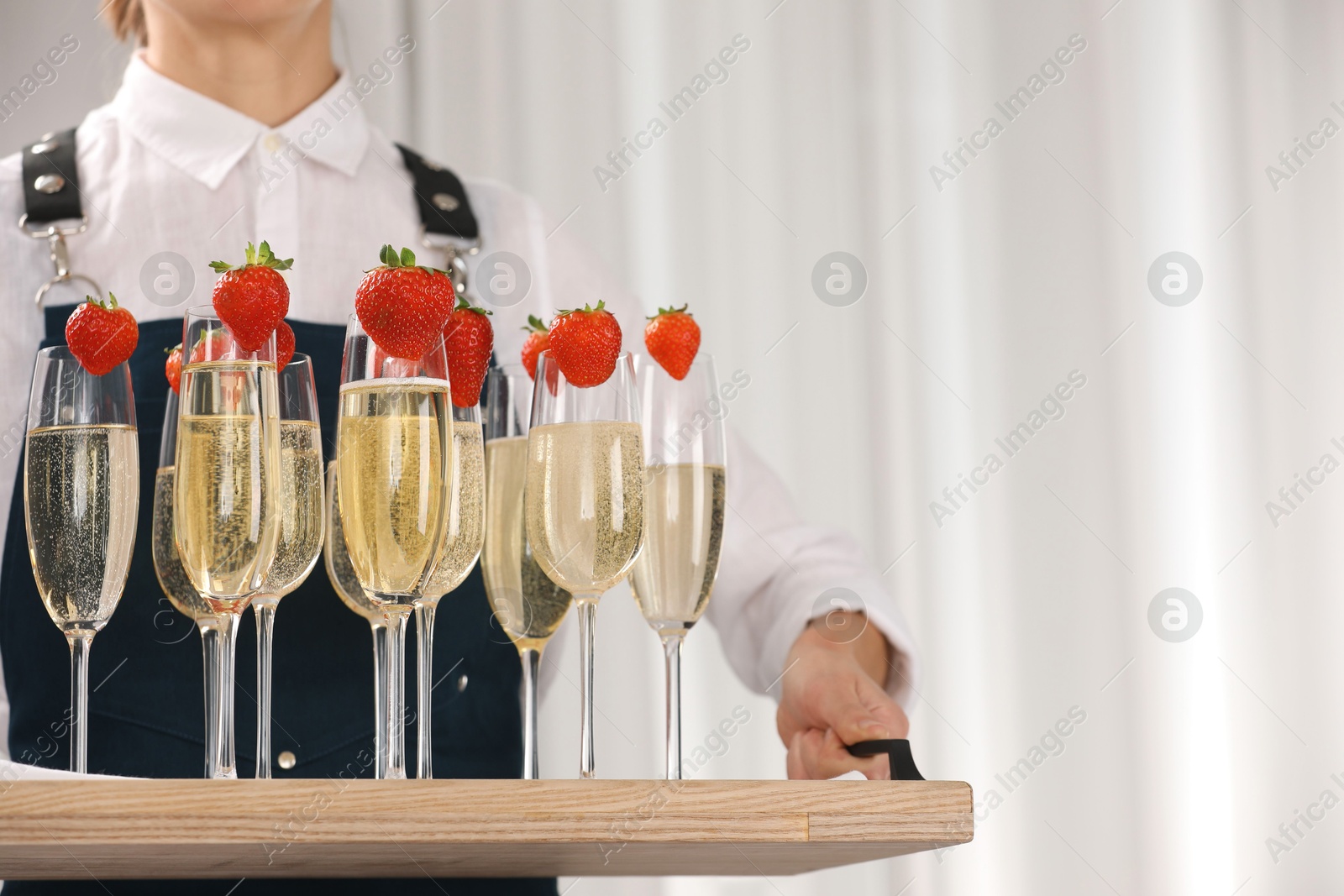 Photo of Waiter holding tray with glasses of champagne indoors, closeup. Space for text