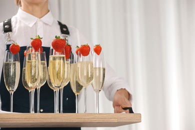 Photo of Waiter holding tray with glasses of champagne indoors, closeup. Space for text