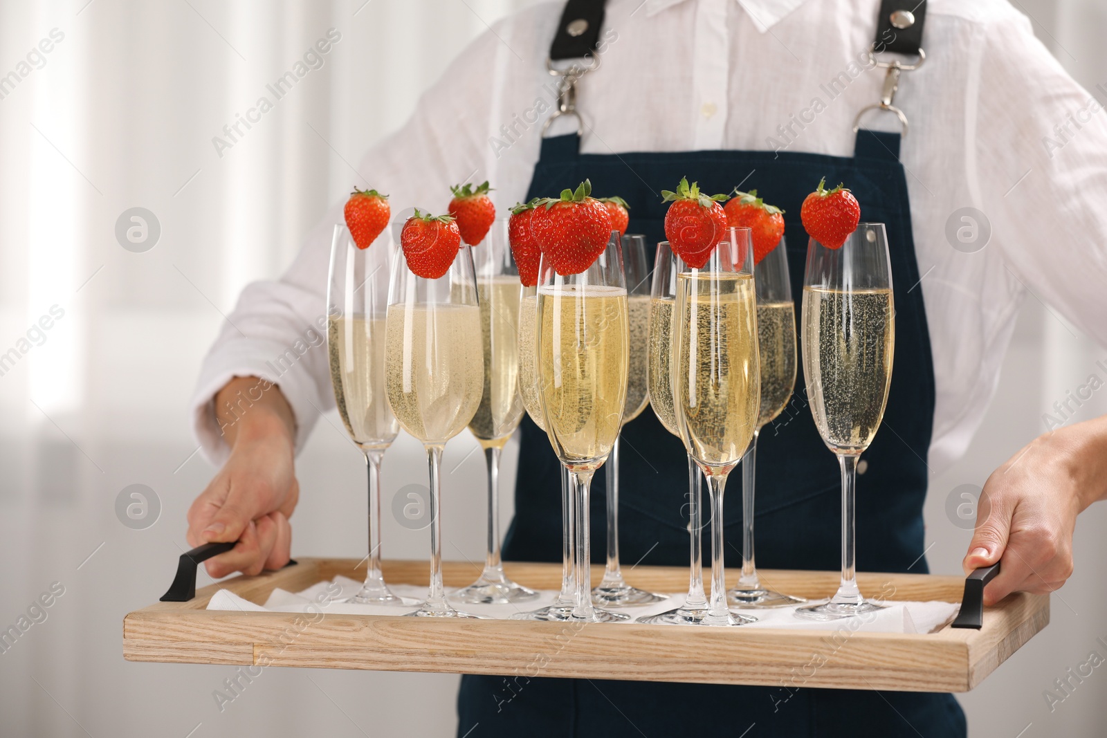 Photo of Waiter holding tray with glasses of champagne indoors, closeup