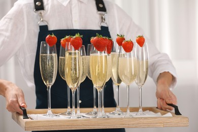 Photo of Waiter holding tray with glasses of champagne indoors, closeup