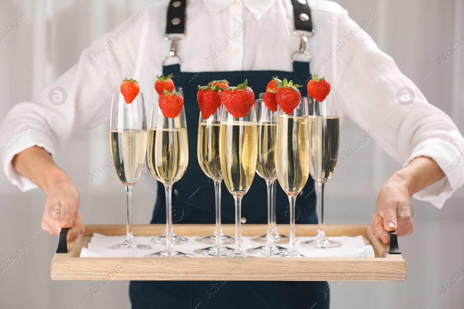 Photo of Waiter holding tray with glasses of champagne indoors, closeup