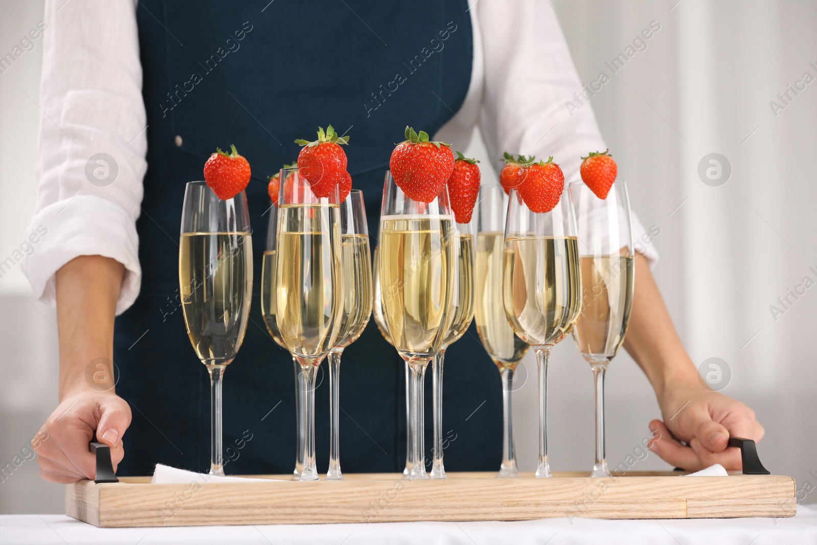 Photo of Waiter holding tray with glasses of champagne at table, closeup