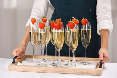 Photo of Waiter holding tray with glasses of champagne at table, closeup