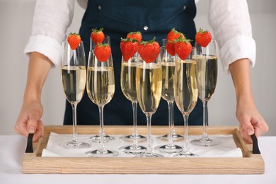 Photo of Waiter holding tray with glasses of champagne at table, closeup