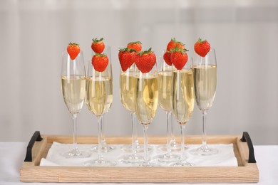 Photo of Champagne in glasses decorated with strawberries on white table