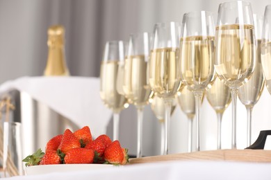 Photo of Champagne in glasses and strawberries on table indoors, closeup