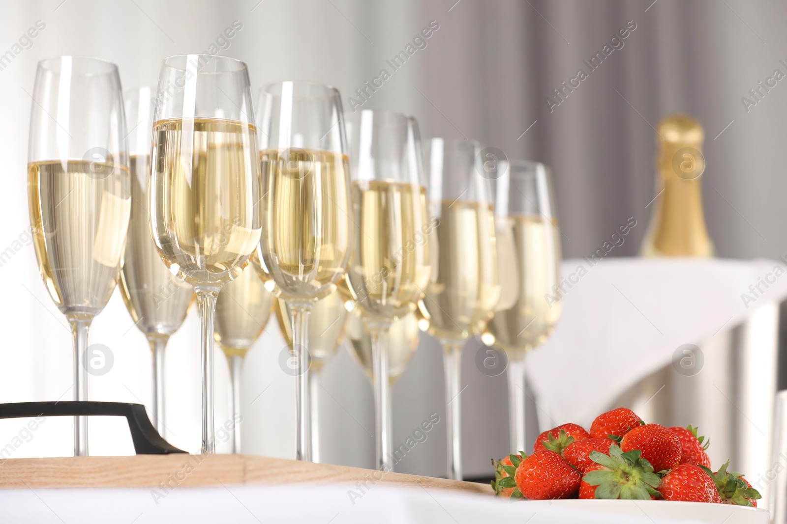 Photo of Champagne in glasses and strawberries on table indoors, closeup