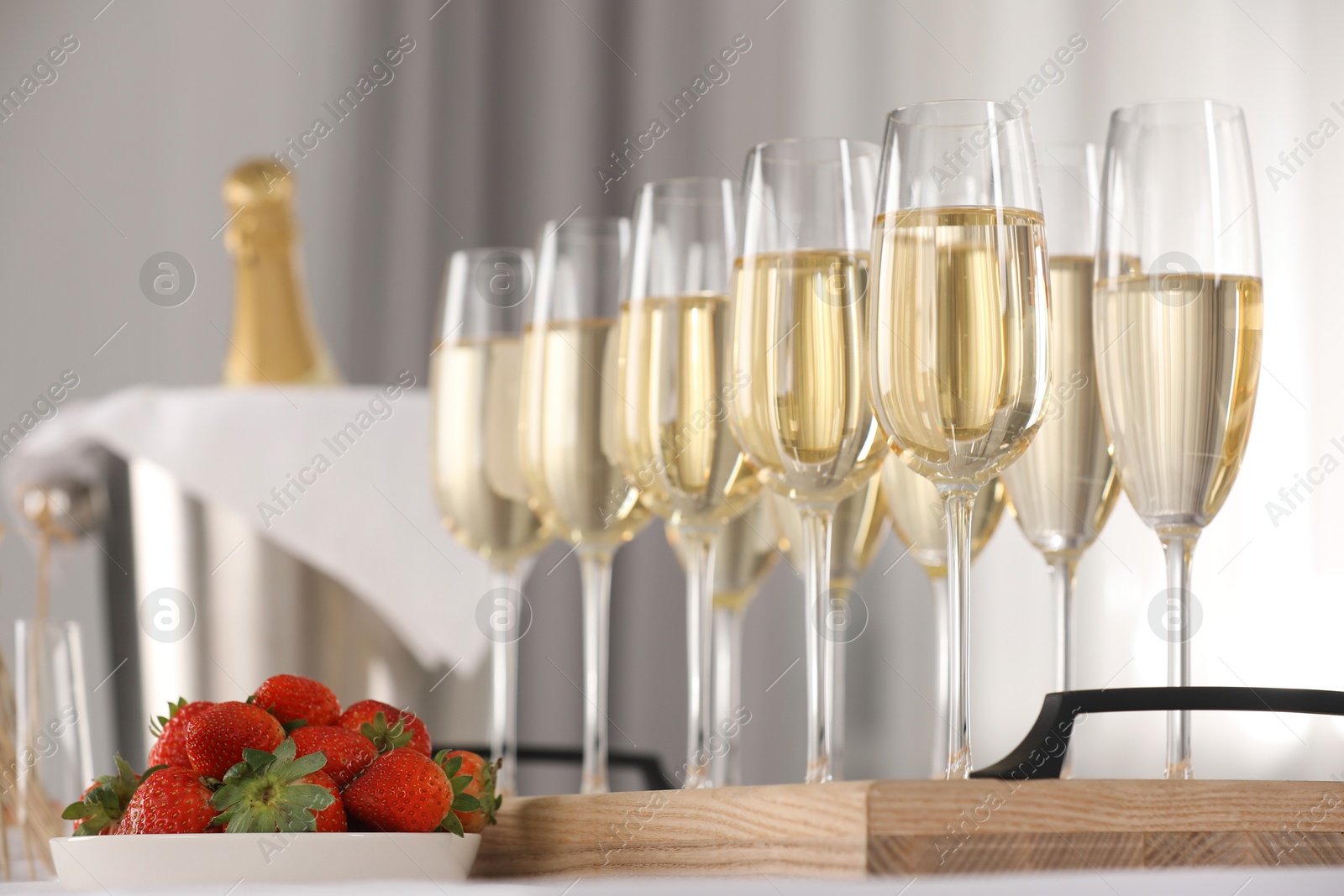 Photo of Champagne in glasses and strawberries on white table indoors