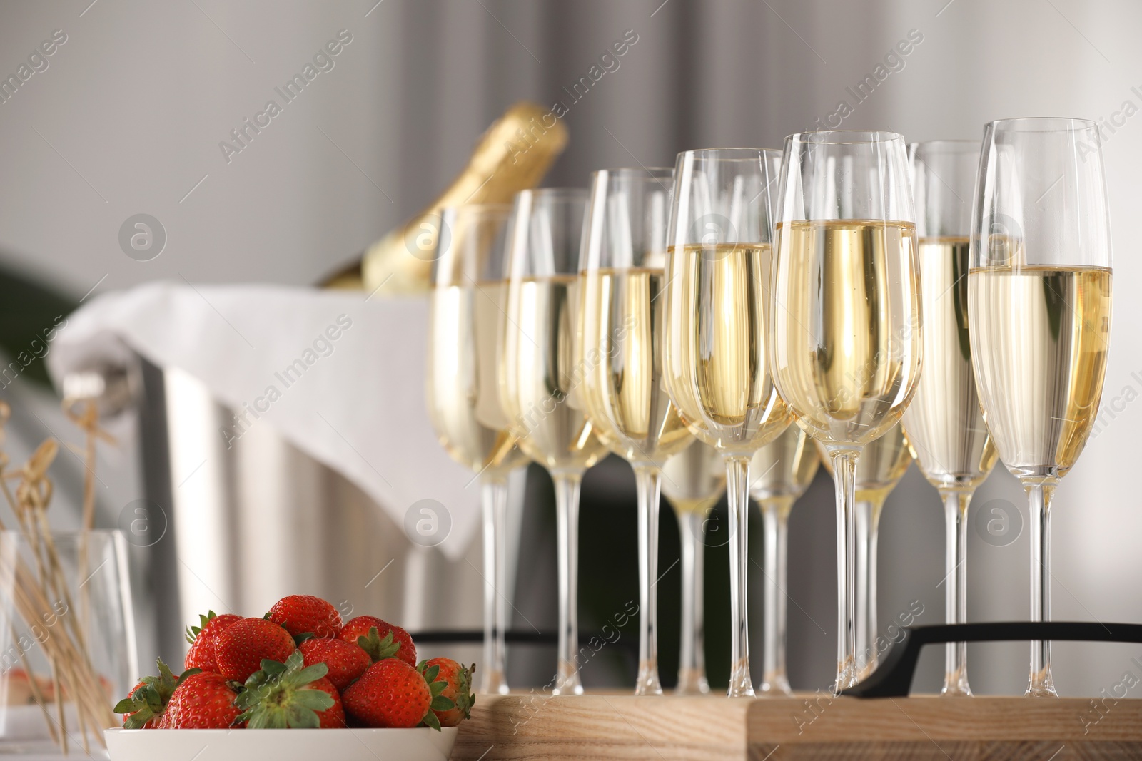 Photo of Champagne in glasses and strawberries on table indoors