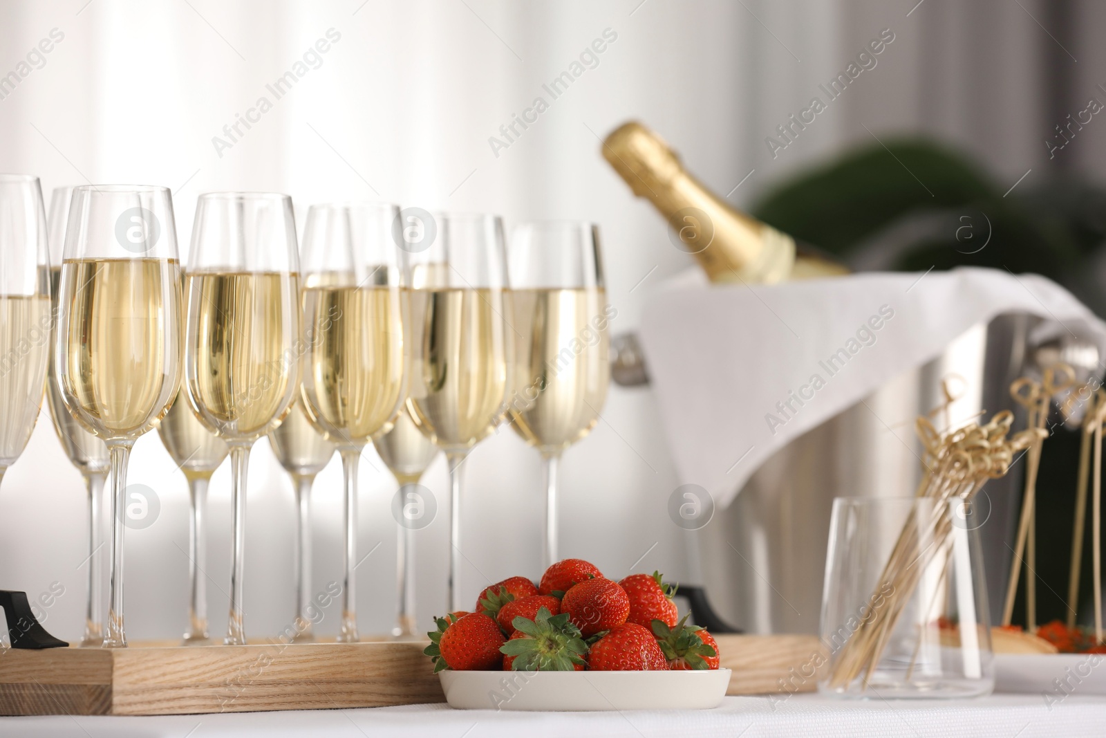 Photo of Champagne in glasses and strawberries on white table indoors