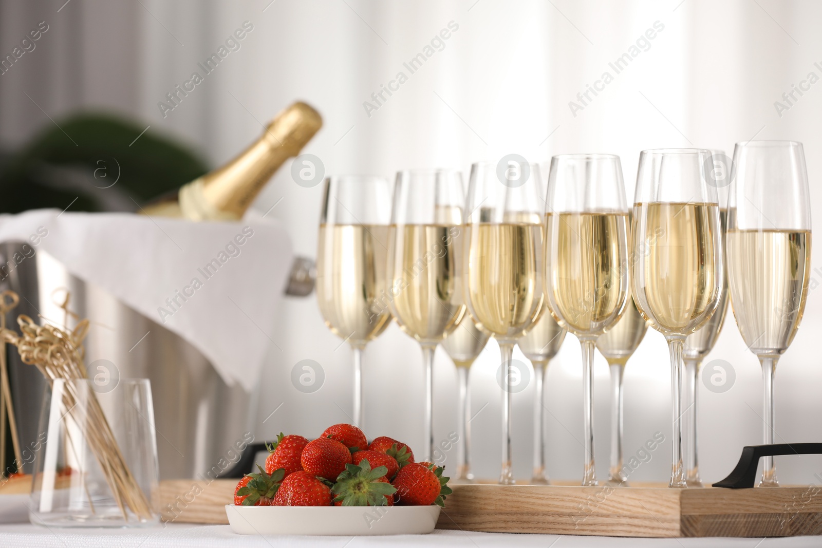 Photo of Champagne in glasses and strawberries on white table indoors