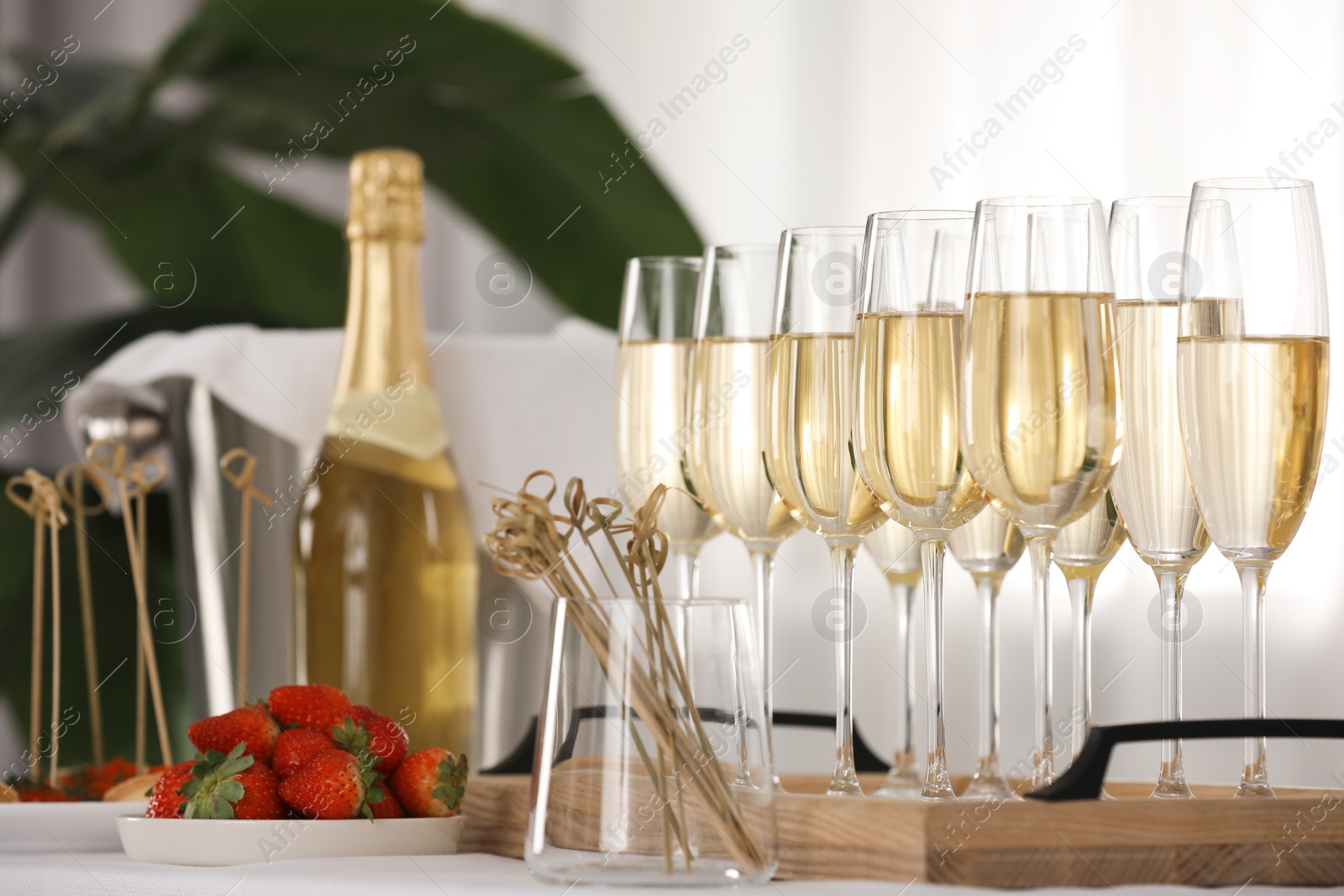 Photo of Champagne in glasses and strawberries on white table indoors