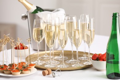 Photo of Champagne, strawberries and canapes with red caviar on white table