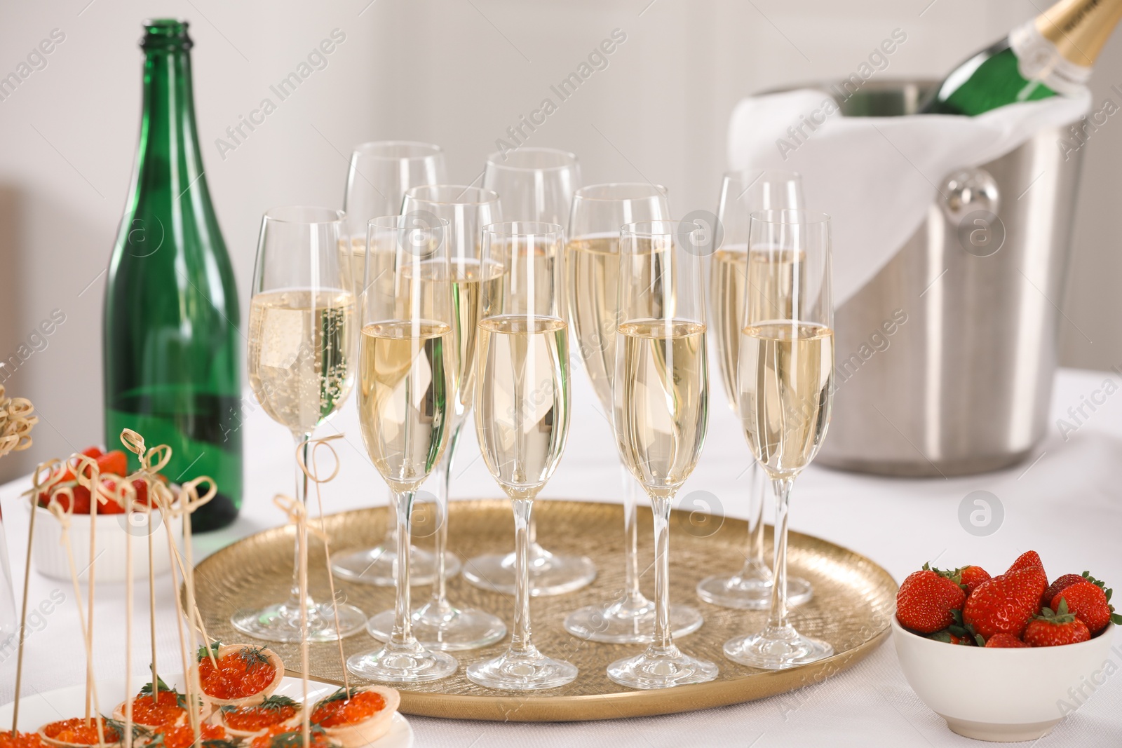 Photo of Champagne, strawberries and canapes with red caviar on white table