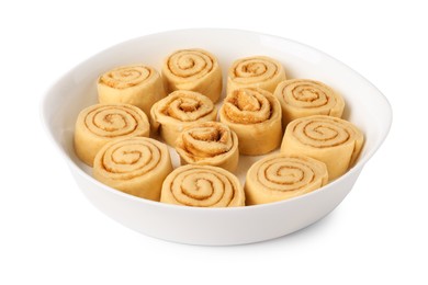 Photo of Raw cinnamon rolls in baking dish isolated on white