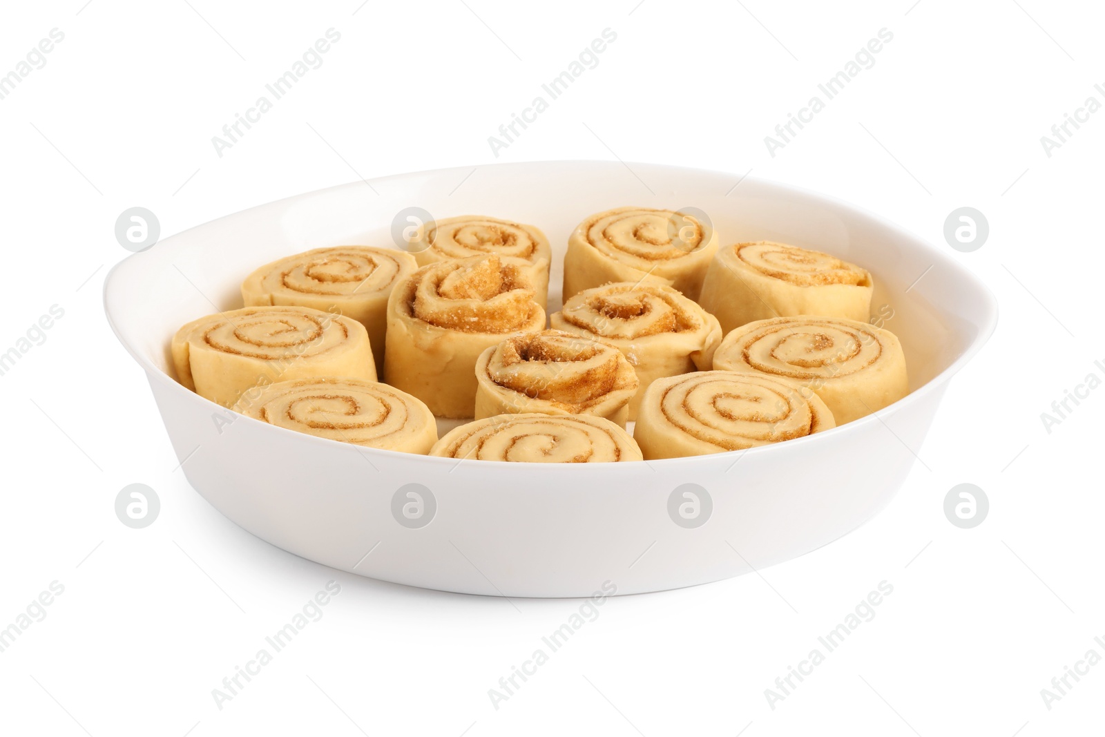 Photo of Raw cinnamon rolls in baking dish isolated on white