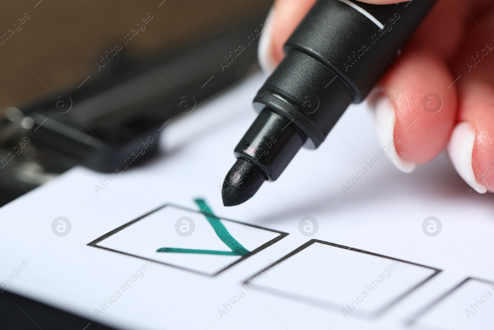 Photo of Woman checking box of paper form at table, closeup