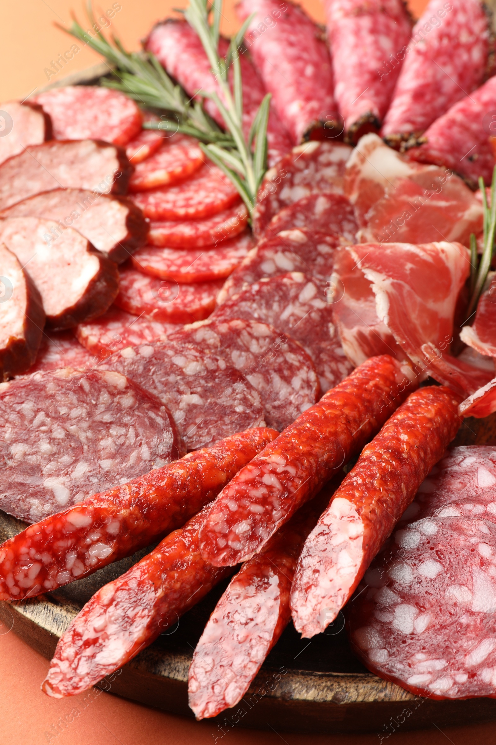 Photo of Different smoked sausages slices on orange background, closeup