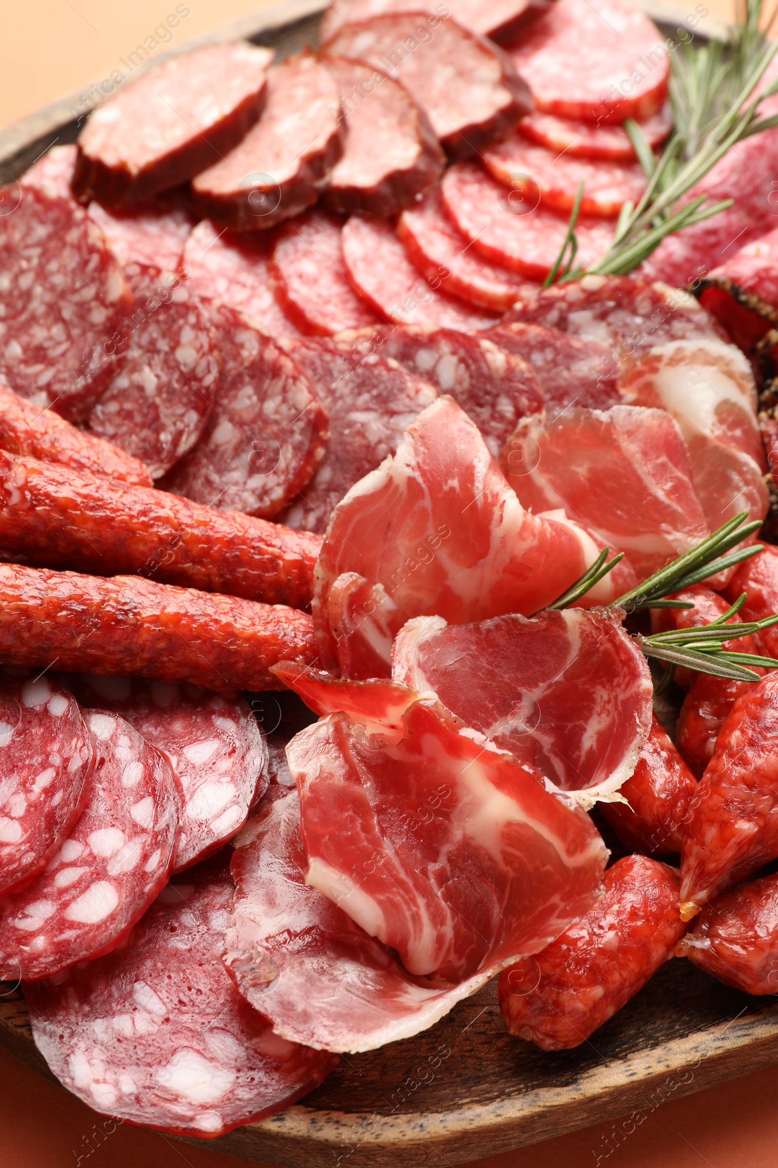 Photo of Different smoked sausages slices on orange background, closeup