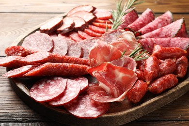 Photo of Different smoked sausages slices served on wooden table closeup