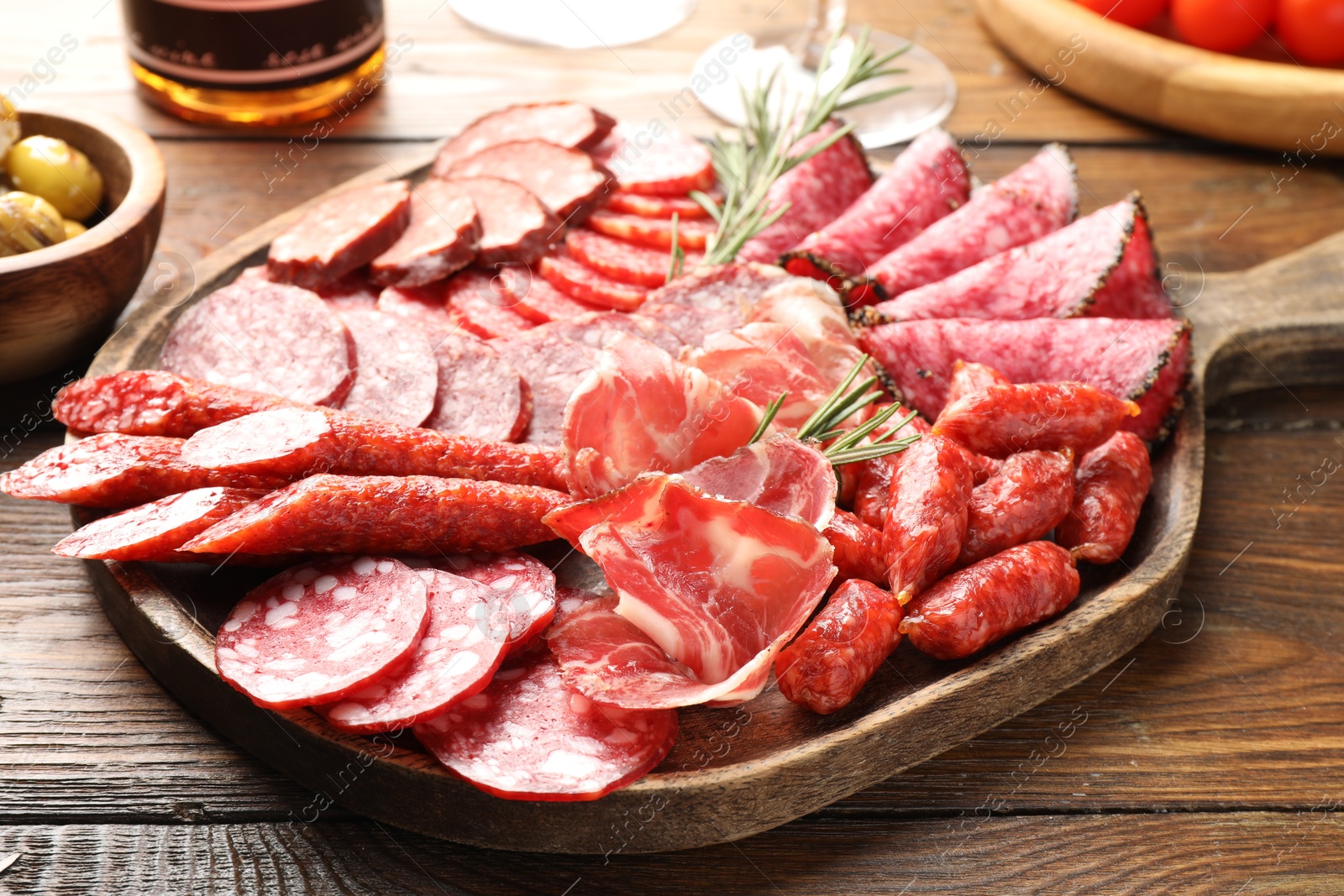 Photo of Different smoked sausages slices served on wooden table closeup