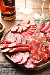 Photo of Different smoked sausages slices served on wooden table closeup